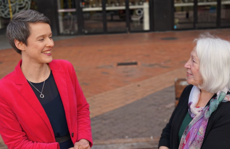 Sarah Thomson - for Mayor of Hamilton City Sarah Thomson, a mayoral candidate for Hamilton city, New Zealand, 2025, is sitting down, talking to an older resident outside the central public library.
